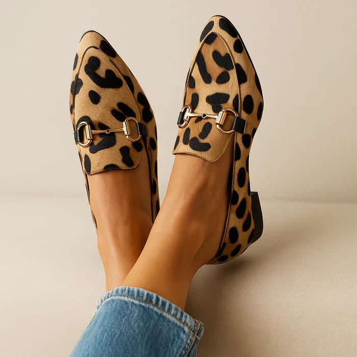 Leopard print loafers with gold buckles worn by a person in a casual setting.
